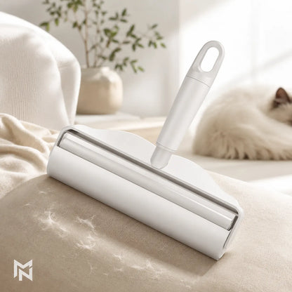 White pet hair removal roller on a beige surface with a cat in the background