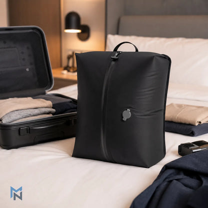 Black compression bag on a bed with folded clothes and an open suitcase.
